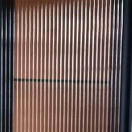 Close-up: bronze reeded glass in black profile.
